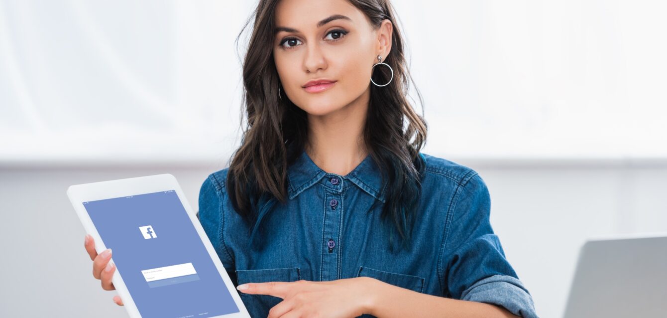 attractive-young-woman-pointing-on-digital-tablet-screen-with-facebook-website